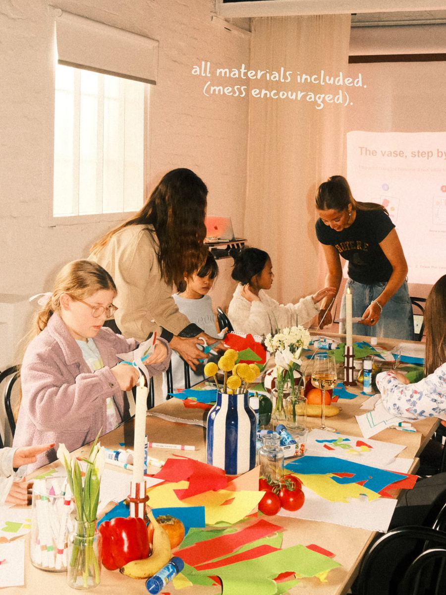 The long table covered in coloured paper, glue, flowers and half-finished work