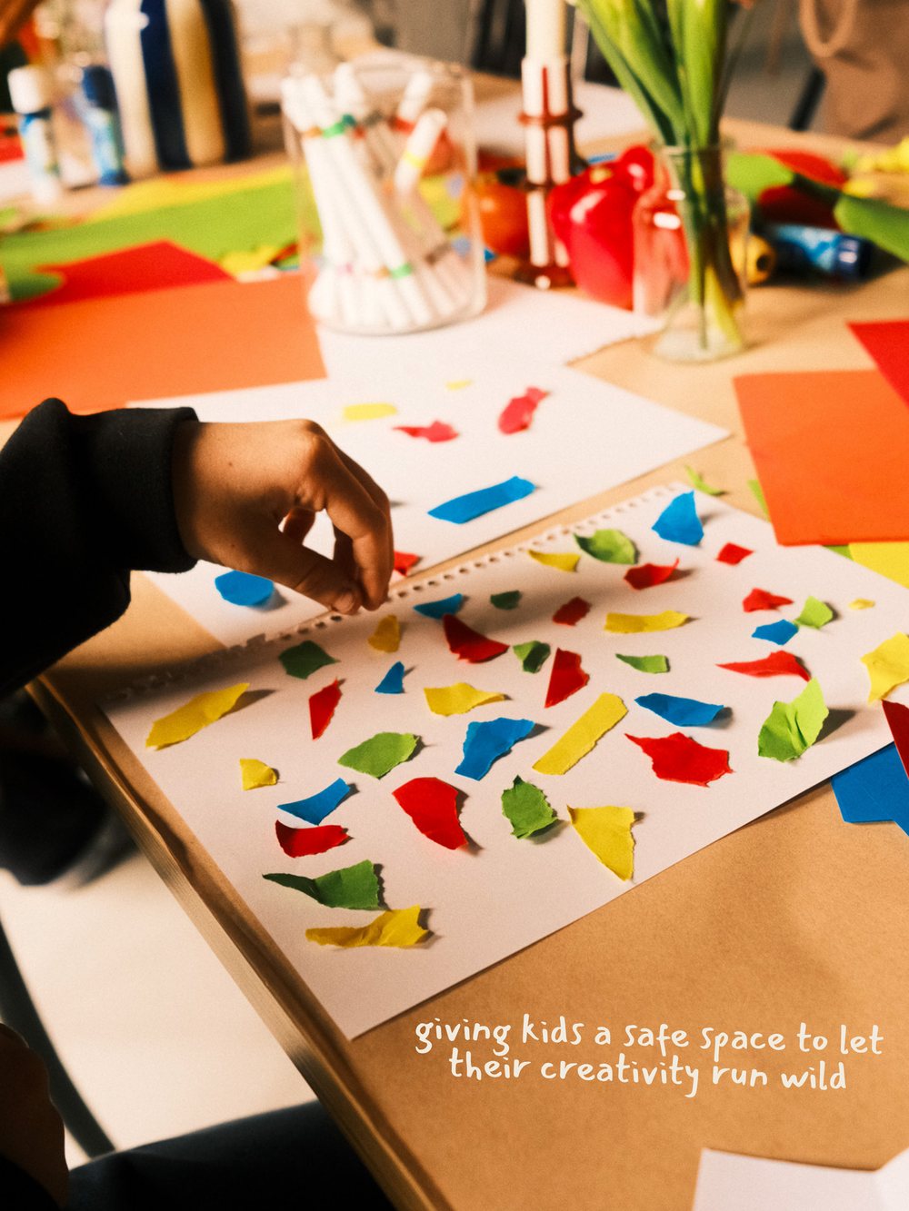 A child placing torn paper shapes across a page